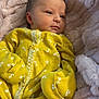 baby, newborn, yellow_clothing, floral_pattern, blanket, soft_texture, infant, cute, sleepwear, portrait, cozy, small_hands, face, head, resting, indoors, peaceful, warm, comfort, child