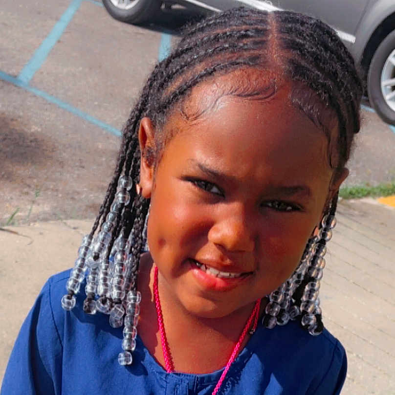 Brayleigh is registered to the contest to win money with this photo: beads, braids, car, casual, child, clothing, cute, face, fashion, hair_style, happy, necklace, outdoor, parking_lot, person, portrait, sidewalk, smile, sunlight, young