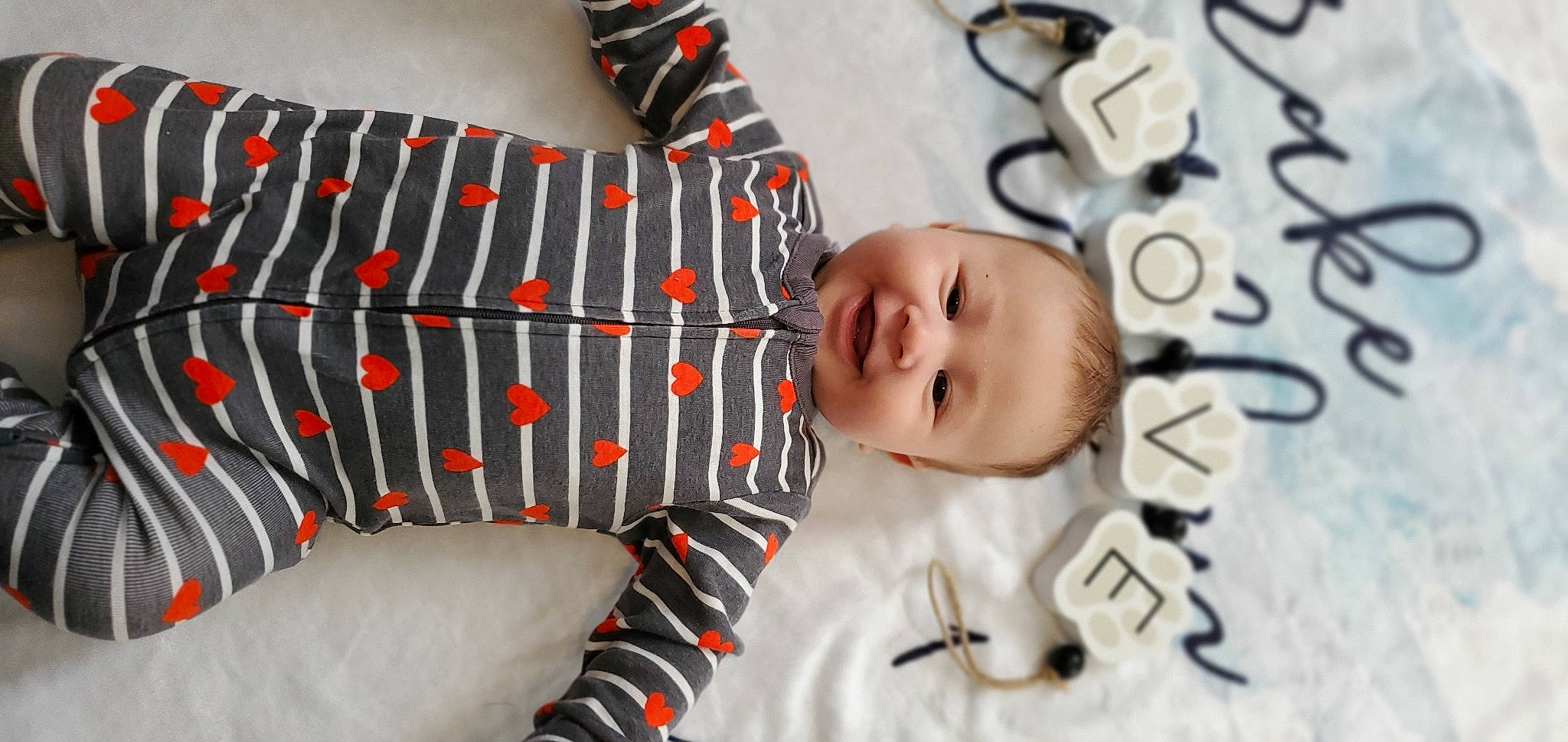 Drake is registered to the contest to win money with this photo: baby, baby_products, baby_sleeping, baby_toddler_clothing, carmine, child, comfort, elbow, fashion_accessory, happy, linens, pattern, person, plaid, portrait_photography, room, sleeve, smile, t_shirt, textile