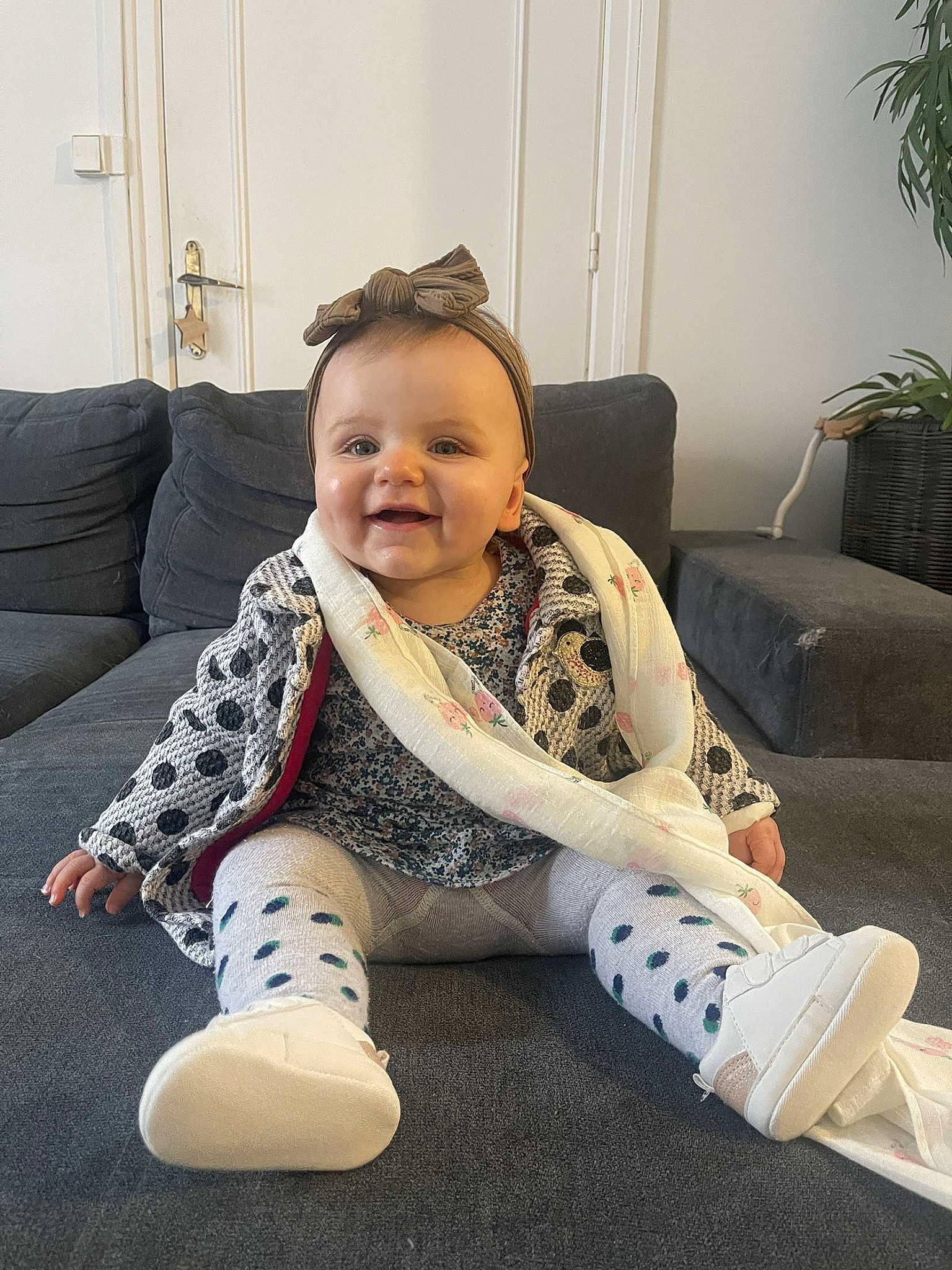 Celestine participe au concours pour gagner de l'argent avec cette photo : baby_toddler_clothing, child, comfort, couch, floor, flooring, happy, head, houseplant, human_leg, joy, knee, lap, leg, person, plant, shoe, sitting, sleeve, smile