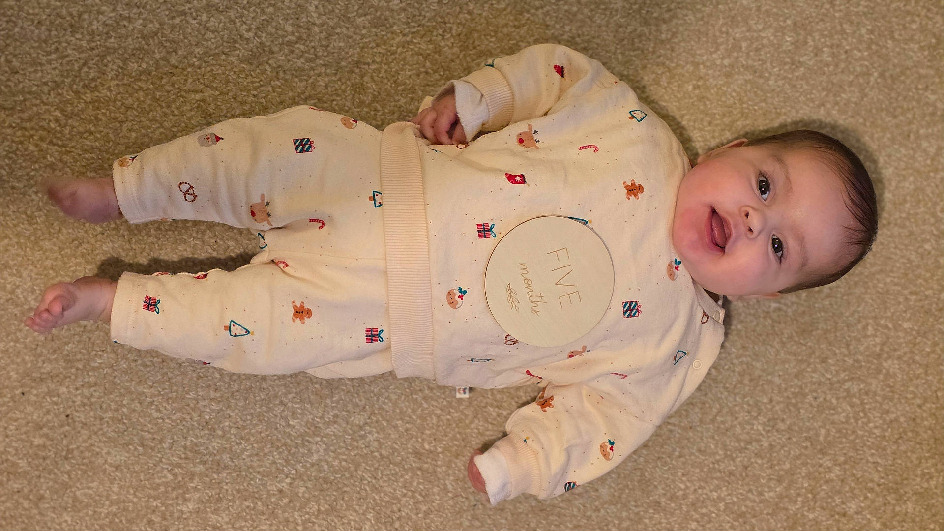 Elsie is registered to the contest to win money with this photo: baby, carpet, celebration, child, clothing, cute, face, floor, foot, hand, happy, head, indoors, infant, lying_down, pajamas, person, portrait, smiling, wooden_plaque