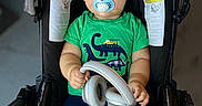 Axel joined the competition — help win amazing prizes! baby, casual, child, clothing, cute, dinosaur_print, feet, green_shirt, hands, headphones, indoors, infant, looking_at_camera, navy_leggings, pacifier, person, portrait, seat, stroller, young_child