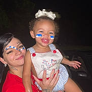 Brooklyn is registered to the contest to win money with this photo: child, toddler, woman, face_paint, tattoos, smile, happy, night, holding, celebration, outdoor, person, red_shirt, white_bow, blue_and_white, face, portrait, cute, joy, together