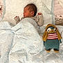 newborn, baby, sleeping, blanket, knitted_toy, plush, bed, soft, striped_clothing, cozy, infant, cute, child, indoors, quiet, resting, toy, patterned, peaceful, comfort