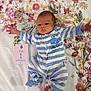 Théonor a rejoint le concours — aidez-le/la à gagner de superbes lots ! baby, newborn, infant, floral_blanket, striped_onesie, blue_and_white, lying_down, card, week_old, stretching_arms, face, head, feet, clothing, pattern, flower, cute, child, portrait, bed