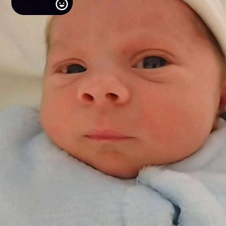 Nolann participe au concours pour gagner de l'argent avec cette photo : baby, beard, blanket, blue_clothing, close_up, communication, expression, face, headwear, indoor, infant, inset, man, newborn, portrait, screen, soft_texture, swaddled, technology, video_call