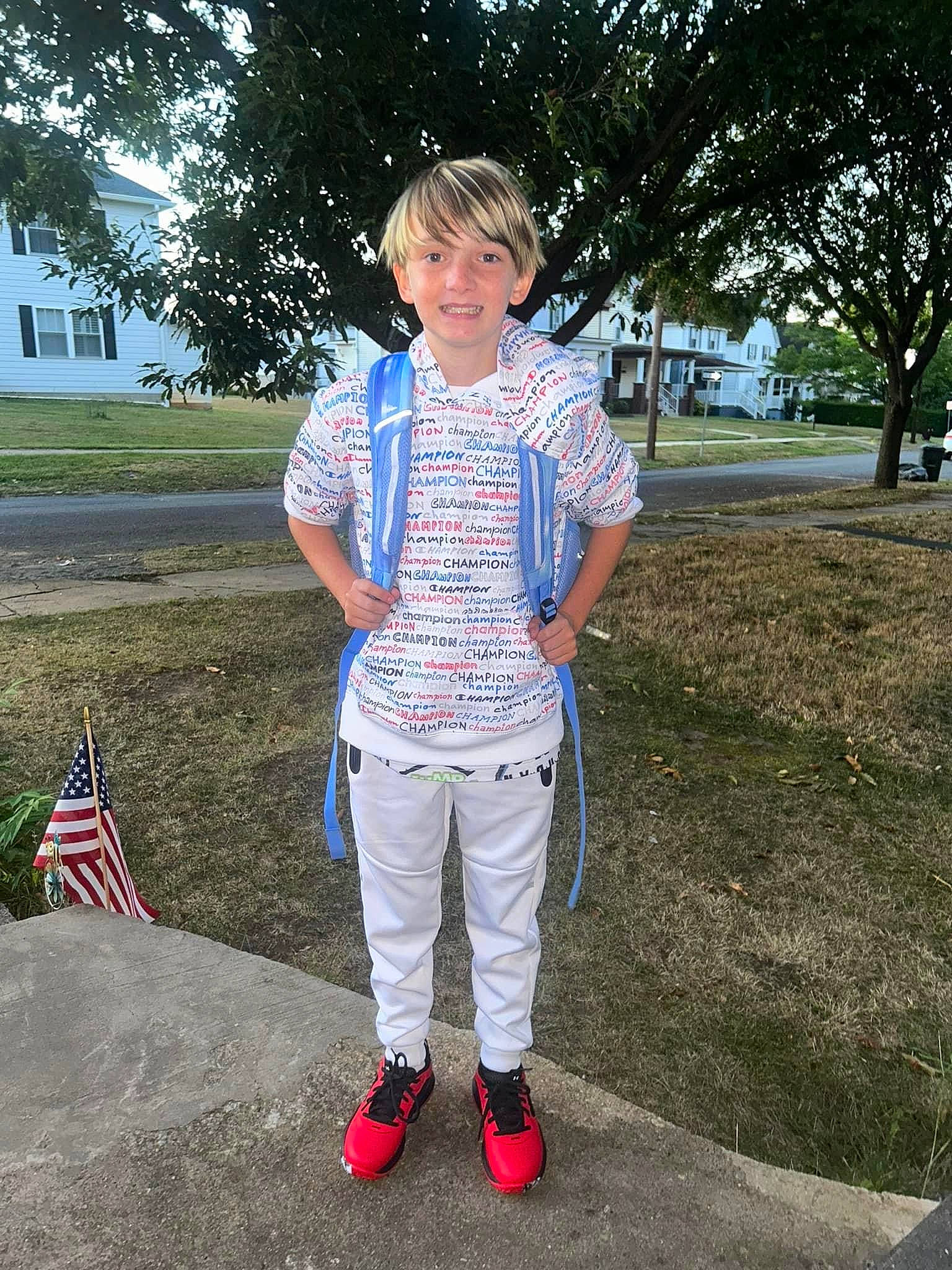 Gavin is registered to the contest to win money with this photo: asphalt, child, denim, electric_blue, eyewear, fashion_accessory, flag, flag_of_the_united_states, footwear, fun, grass, joy, leisure, pattern, person, plaid, recreation, smile, t_shirt, tree