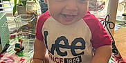 Roberto joined the competition — help win amazing prizes! baby, child, smiling, sitting, diaper, red_shirt, tablecloth, indoor, plant, window, sunlight, toy, household_items, face, hand, foot, happy, person, clothing, tongue