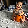 Roberto joined the competition — help win amazing prizes! baby, child, pumpkin, bed, pillow, blanket, smile, happy, indoors, cute, infant, clothing, foot, head, room, furniture, pattern, sitting, holding, cozy