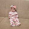 Osiyo is registered to the contest to win money with this photo: baby, beige, child, clothing, comfortable, couch, cute, headband, home, indoor, infant, looking_at_camera, onesie, person, pink_bow, portrait, seated, soft_fabric, strawberry_pattern, young_child