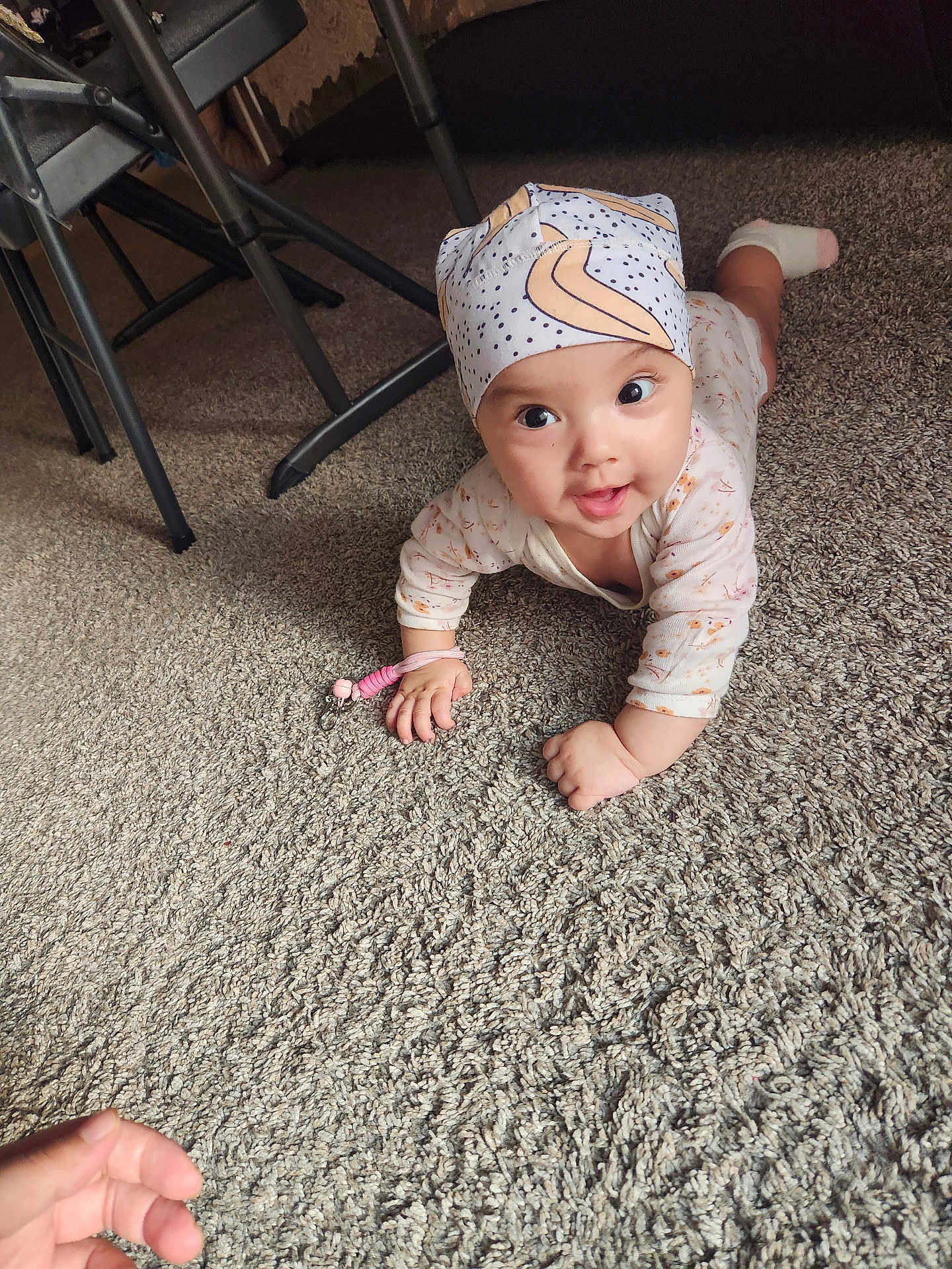 Osiyo is registered to the contest to win money with this photo: baby, crawling, carpet, headscarf, hand, indoor, child, cute, patterned_clothing, floor, furniture, person, infant, reaching, playful, expression, room, legs, socks, toy