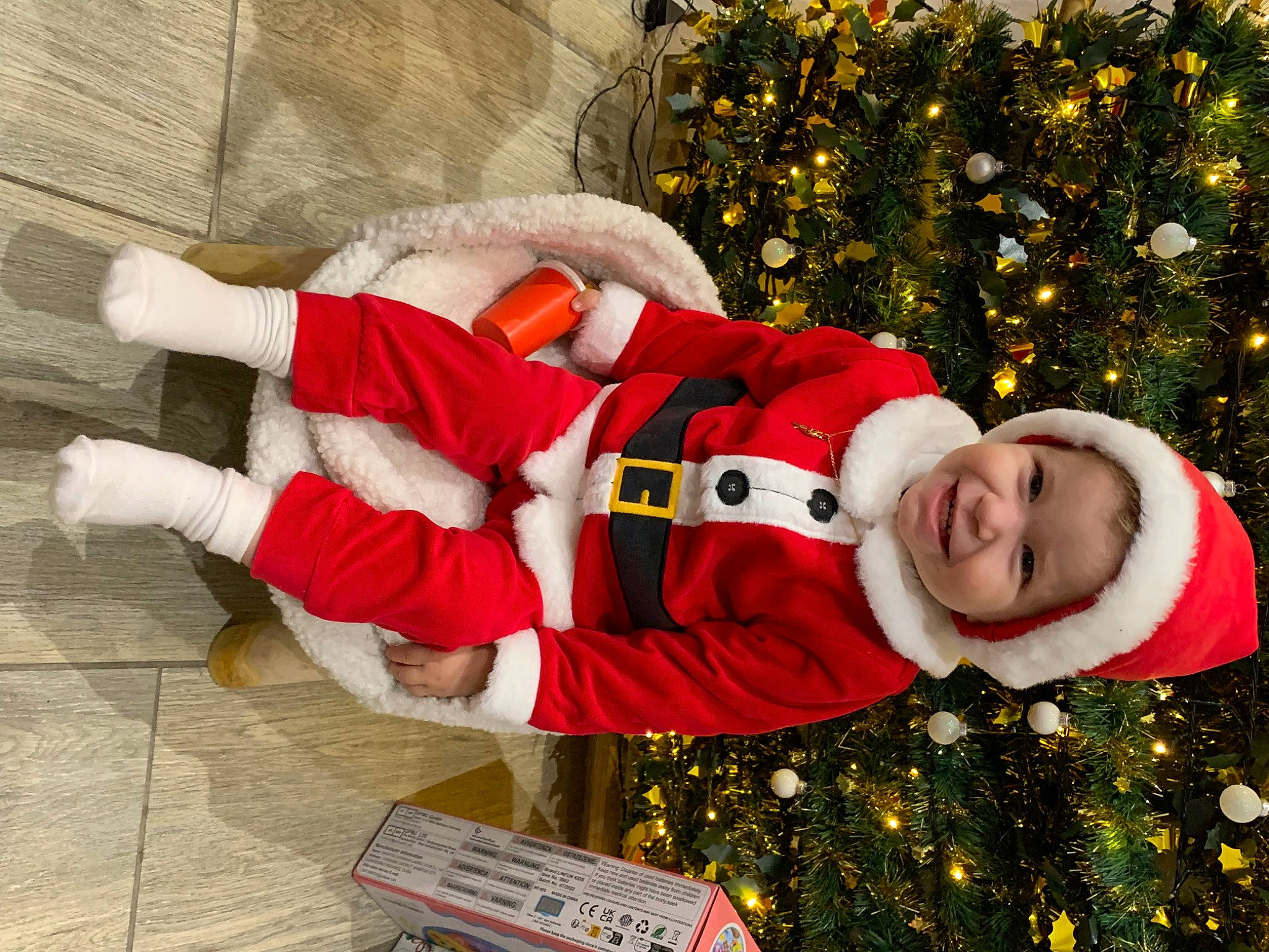 Lorenzo participe au concours pour gagner de l'argent avec cette photo : child, christmas, christmas_decoration, christmas_eve, christmas_ornament, christmas_tree, event, facial_expression, fictional_character, happy, headwear, holiday, holiday_ornament, human_body, lap, ornament, person, plant, santa_claus, sleeve