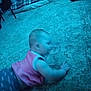 baby, baby_girl, blue_light, blur, carpet, child, clothing, crawling, floor, furniture, hand, head, indoor, infant, living_room, pants, person, pink_top, plaid_pillow, young_child