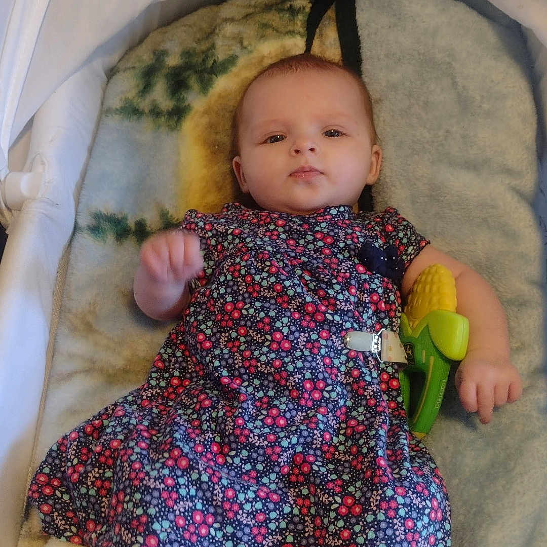 Charlotte Elishka joined the competition — help win amazing prizes! baby, bassinet, blanket, calm, child, closeup, colorful, comfort, corn_toy, cute, dress, floral_pattern, indoor, infant, lying_down, person, portrait, soft_texture, toy, young_child
