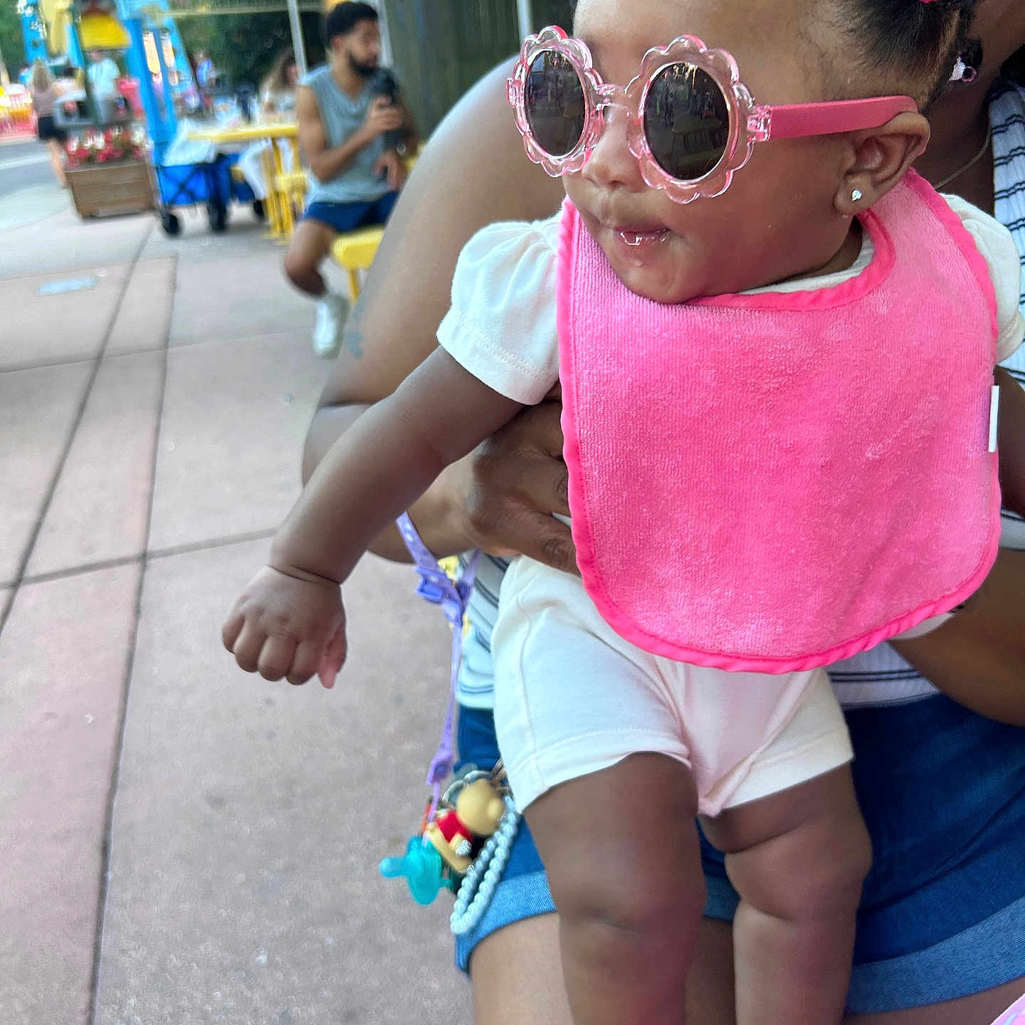 A Niylah joined the competition — help win amazing prizes! accessory, adult, baby, casual_clothing, child, colorful, curious, fun, holding, outdoor, people, person, pink_bib, playful, sidewalk, street, summer, sunglasses, sunny, umbrella