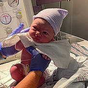 Paisley joined the competition — help win amazing prizes! newborn, baby, hospital, medical_equipment, gloves, blanket, striped_hat, infant, person, bed, monitor, medical, cute, newborn_care, healthcare, human, skin, towel, scrunched_face, holding