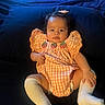 baby, bed, black_hair, checkered_dress, child, cozy, dark_background, dress, eyes, face, fashion, hair_clip, hands, indoors, infant, knee_socks, legs, portrait, sitting, strawberry_pattern