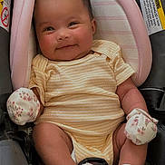 Amara is registered to the contest to win money with this photo: baby, infant, child, smiling, car_seat, onesie, striped_clothing, mittens, socks, floral_pattern, headrest, buckle, seat_padding, rosy_cheeks, portrait, closeup, hands, legs, warning_label, pink