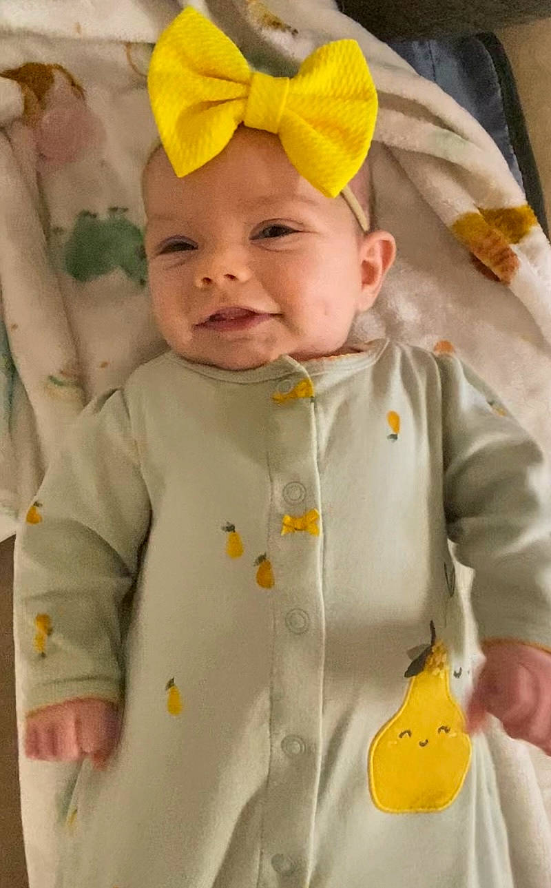 Elliana is registered to the contest to win money with this photo: baby, baby_products, baby_toddler_clothing, cheek, child, clothing, collar, face, facial_expression, happy, head, headwear, outerwear, pattern, person, product, skin, sleeve, smile, toddler