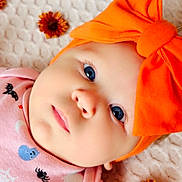 Olivia is registered to the contest to win money with this photo: baby, infant, face, blue_eyes, orange_bow, headband, pink_clothing, halloween_theme, pumpkin, bat, spider, blanket, flower, orange_flower, cute, portrait, close_up, child, lying_down, soft_texture