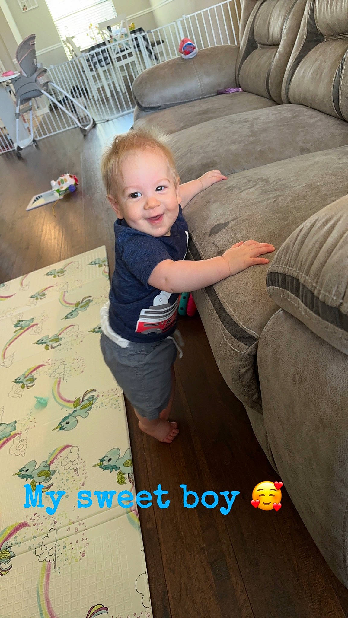 Hunter is registered to the contest to win money with this photo: baby, child, comfort, couch, floor, flooring, fun, hardwood, houseplant, joy, leisure, living_room, person, play, room, shorts, sitting, smile, t_shirt, thigh