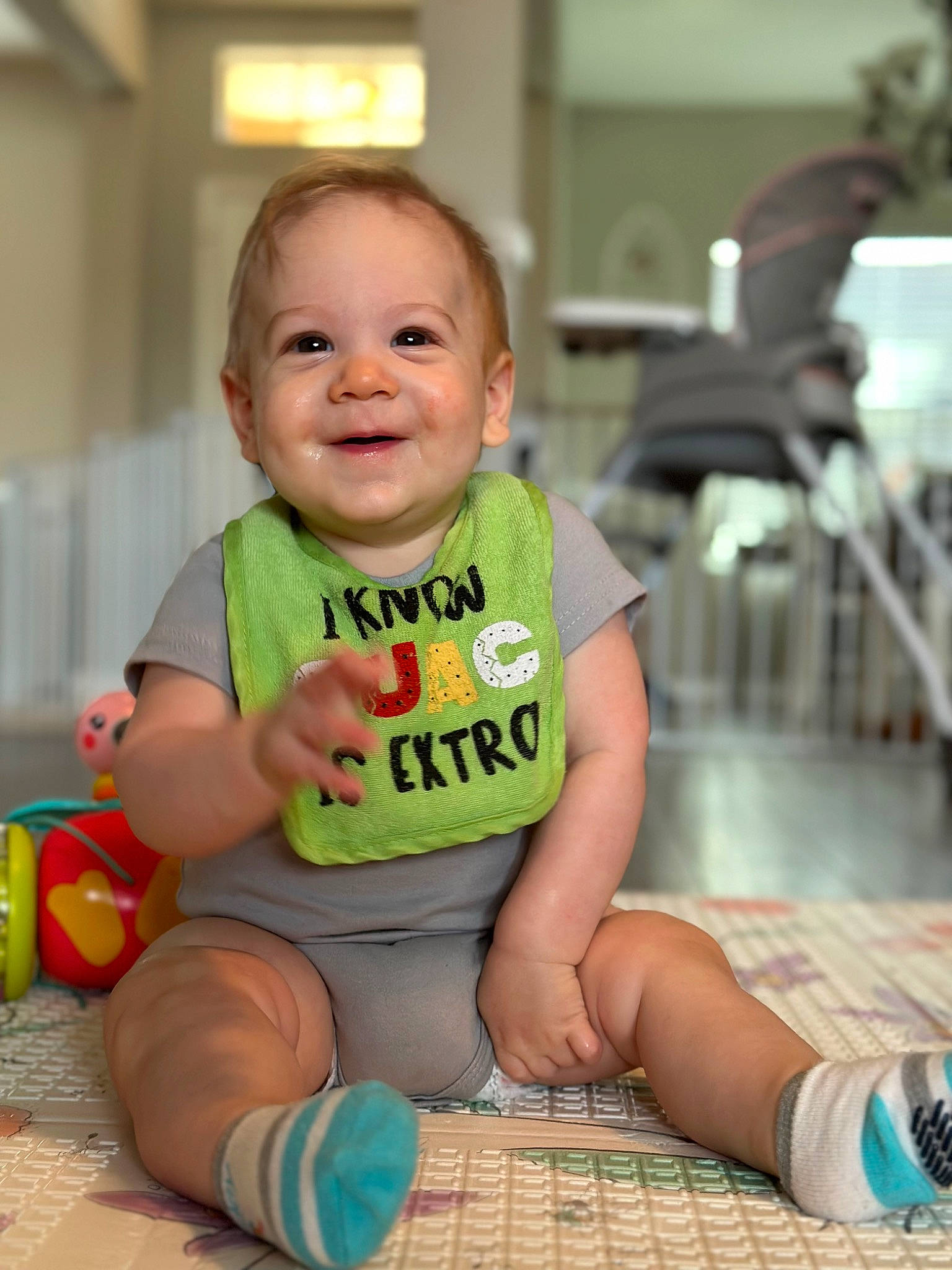 Hunter is registered to the contest to win money with this photo: baby, baby_products, baby_toddler_clothing, cheek, child, facial_expression, floor, flooring, foot, fun, happy, human_leg, joy, knee, person, sitting, skin, sleeve, smile, sock