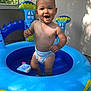 toddler, child, diaper, inflatable_pool, water, outdoor, sunlight, happy, smiling, baby, play, summer, blue, plastic, toy, backyard, skin, face, person, fun