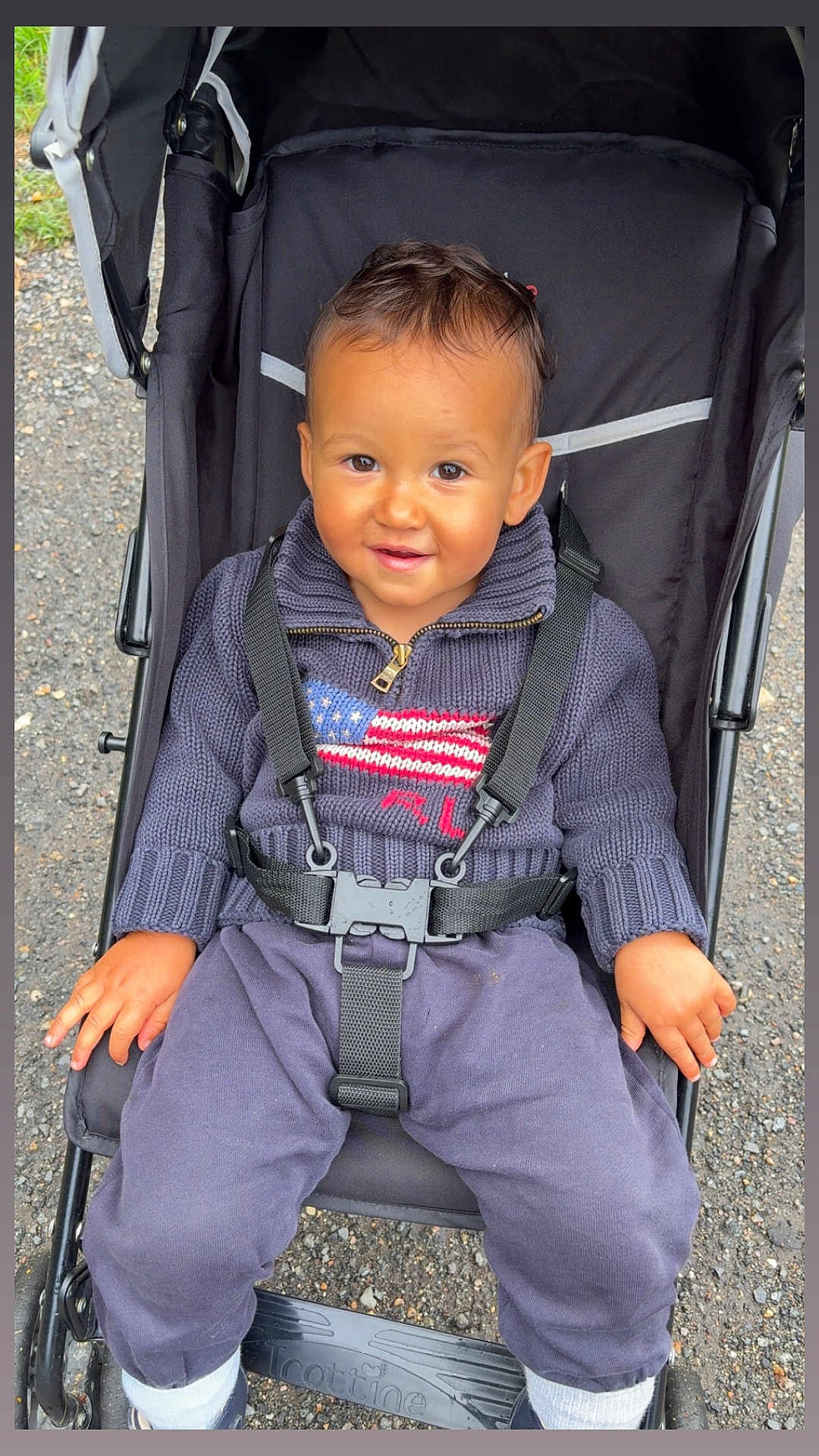 Ayden a rejoint le concours — aidez-le/la à gagner de superbes lots ! american_flag, baby, casual, child, clothing, daylight, face, footwear, hands, happy, head, jogging_pants, outdoor, pavement, person, portrait, seatbelt, stroller, sweater, toddler