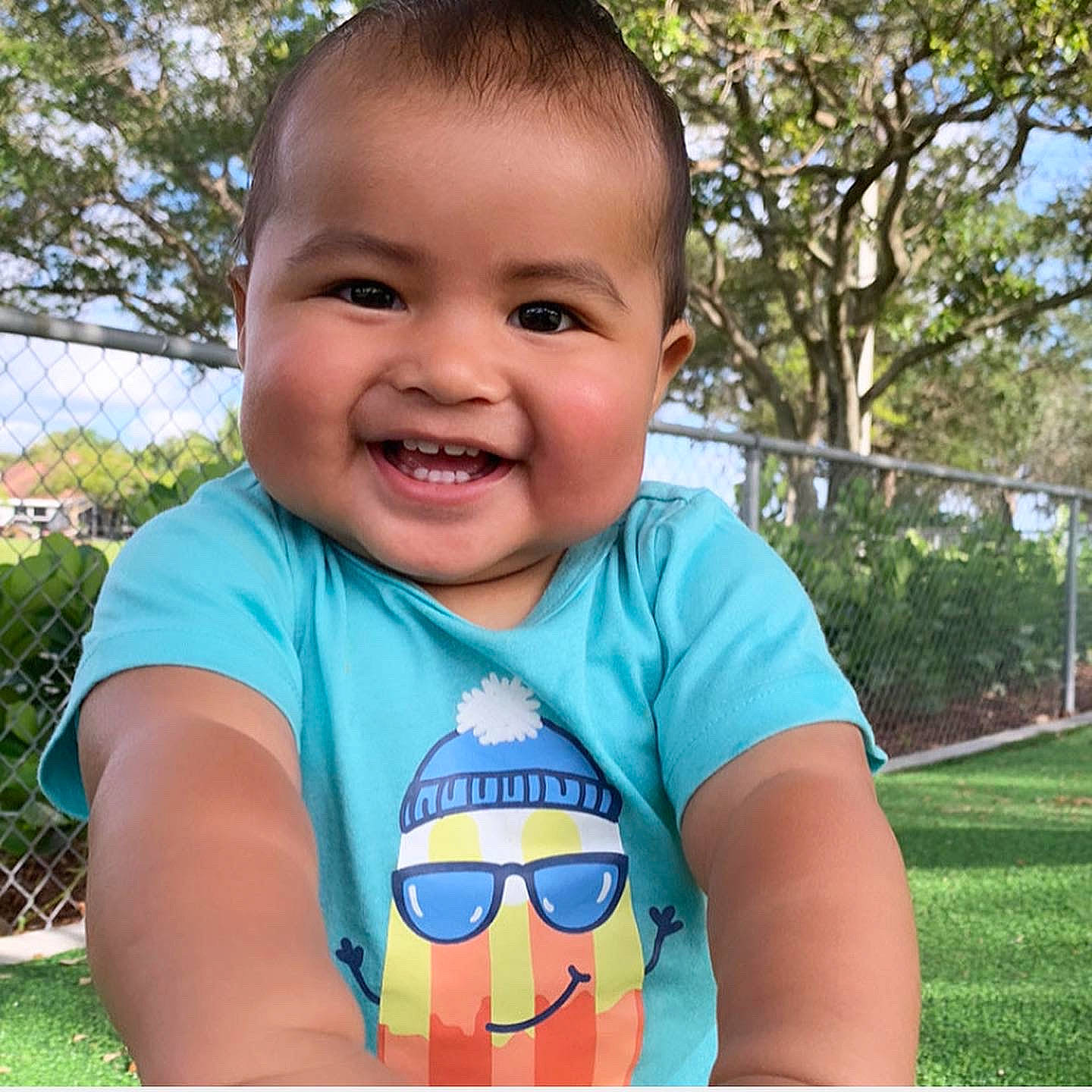 James is registered to the contest to win money with this photo: baby_toddler_clothing, cool, face, facial_expression, goggles, grass, happy, head, joy, mouth, neck, outerwear, person, plant, shirt, skin, sleeve, smile, sunglasses, t_shirt