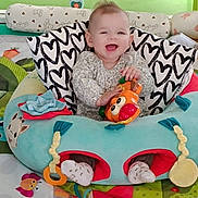 Jade a rejoint le concours — aidez-le/la à gagner de superbes lots ! baby, smiling, toy, baby_seat, cushion, colorful, nursery, child, happy, infant, patterned_blanket, soft_toys, play_area, cute, indoor, person, comfort, fun, cheerful, clothing