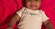 Nova Reign is registered to the contest to win money with this photo: adorable, baby, blanket, child, clothing, cozy, cute, expression, face, hair_bows, happy, indoor, infant, lying_down, person, pink_clothing, portrait, smiling, tongue_out, young_child