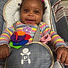 Nova Reign is registered to the contest to win money with this photo: baby, baby_seat, cheerful, child, close_up, colorful_clothing, cute, face, hair_accessories, hands, happy, indoor, infant, multicolor, playful, portrait, seat, smile, straps, toy