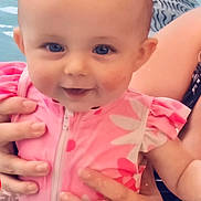 Lya a rejoint le concours — aidez-le/la à gagner de superbes lots ! baby, child, swimsuit, pink, water, pool, smile, face, hands, person, blue_eyes, skin, adult, support, sitting, cute, joyful, summer, fun, closeup
