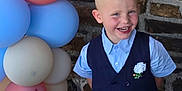 Enzo participe au concours pour gagner de l'argent avec cette photo : child, boy, smiling, balloons, vest, shirt, stone_wall, blue, red, pastel_colors, happy, portrait, party, celebration, flower_boutonniere, short_hair, indoors, cute, formal_wear, standing