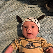 Ziah joined the competition — help win amazing prizes! baby, baby_garment, blue_blanket, child, clothing, cute, expression, eyes, face, hat, headwear, indoor, infant, lying_down, monster_truck, portrait, skin, smile, yellow_shirt, young_child