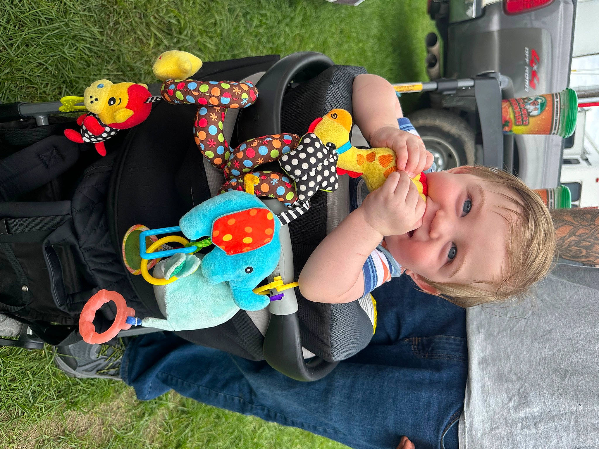 Jake joined the competition — help win amazing prizes! automotive_exterior, baby, baby_toddler_clothing, child, fun, grass, happy, lap, leisure, mammal, people, person, plant, recreation, sitting, smile, tire, toddler, vehicle, vertebrate