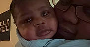 Danny is registered to the contest to win money with this photo: baby, infant, adult, glasses, face, video_call, blanket, indoor, hug, smile, person, technology, screen, portrait, closeup, family, love, affection, communication, home
