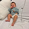 baby, smiling, hospital_bed, diaper, sweater, medical_sensor, foot, pillow, white_sheet, infant, child, cute, resting, indoors, healthcare, person, happy, young_child, lying_down, cozy