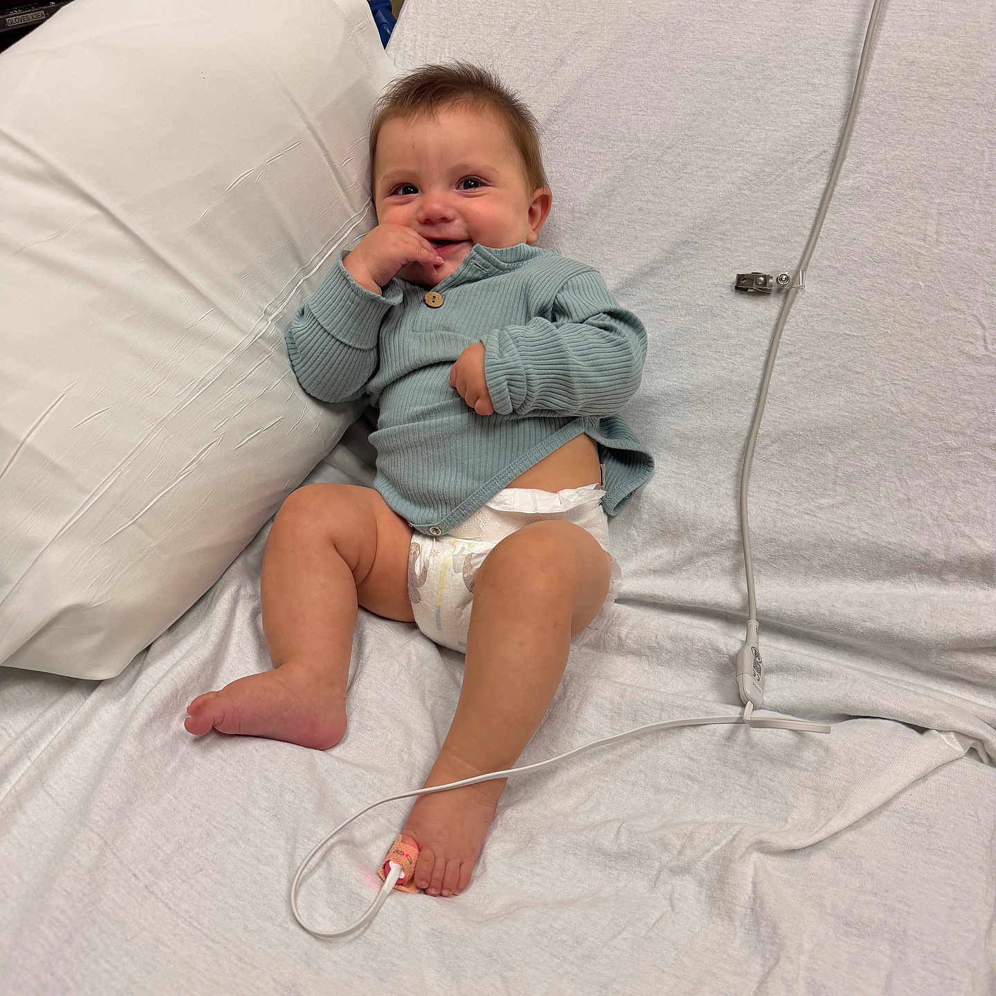 Ziloh joined the competition — help win amazing prizes! baby, smiling, hospital_bed, diaper, sweater, medical_sensor, foot, pillow, white_sheet, infant, child, cute, resting, indoors, healthcare, person, happy, young_child, lying_down, cozy