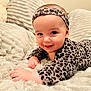 baby, infant, smiling, leopard_print, headband, blanket, soft_texture, couch, cute, child, happy, portrait, clothing, toddler, indoor, face, hand, skin, warm_light, cozy