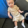 baby, blue_cushion, casual, child, couch, curious, expression, face, furniture, hat, indoor, light_hair, pacifier, person, relaxing, seated, shirt, shorts, sock, toddler