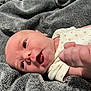 Clementine is registered to the contest to win money with this photo: baby, infant, blanket, face, hand, newborn, person, skin, clothing, sleepwear, lying_down, expression, cute, closeup, soft_texture, cozy, fist, mouth_open, eyes_open, resting
