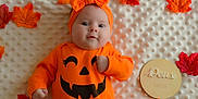 Joy a rejoint le concours — aidez-le/la à gagner de superbes lots ! baby, infant, orange_clothing, headband, pumpkin_face, autumn_leaves, blanket, milestone, cute, portrait, lying_down, fall, seasonal, holiday, child, smiling, decor, soft_texture, celebration, happy