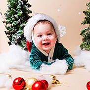 Aiden is registered to the contest to win money with this photo: baby, child, smiling, christmas, holiday, festive, santa_hat, green_clothing, ornaments, red, gold, snow, fake_snow, christmas_tree, decorations, happy, portrait, indoor, cute, celebration