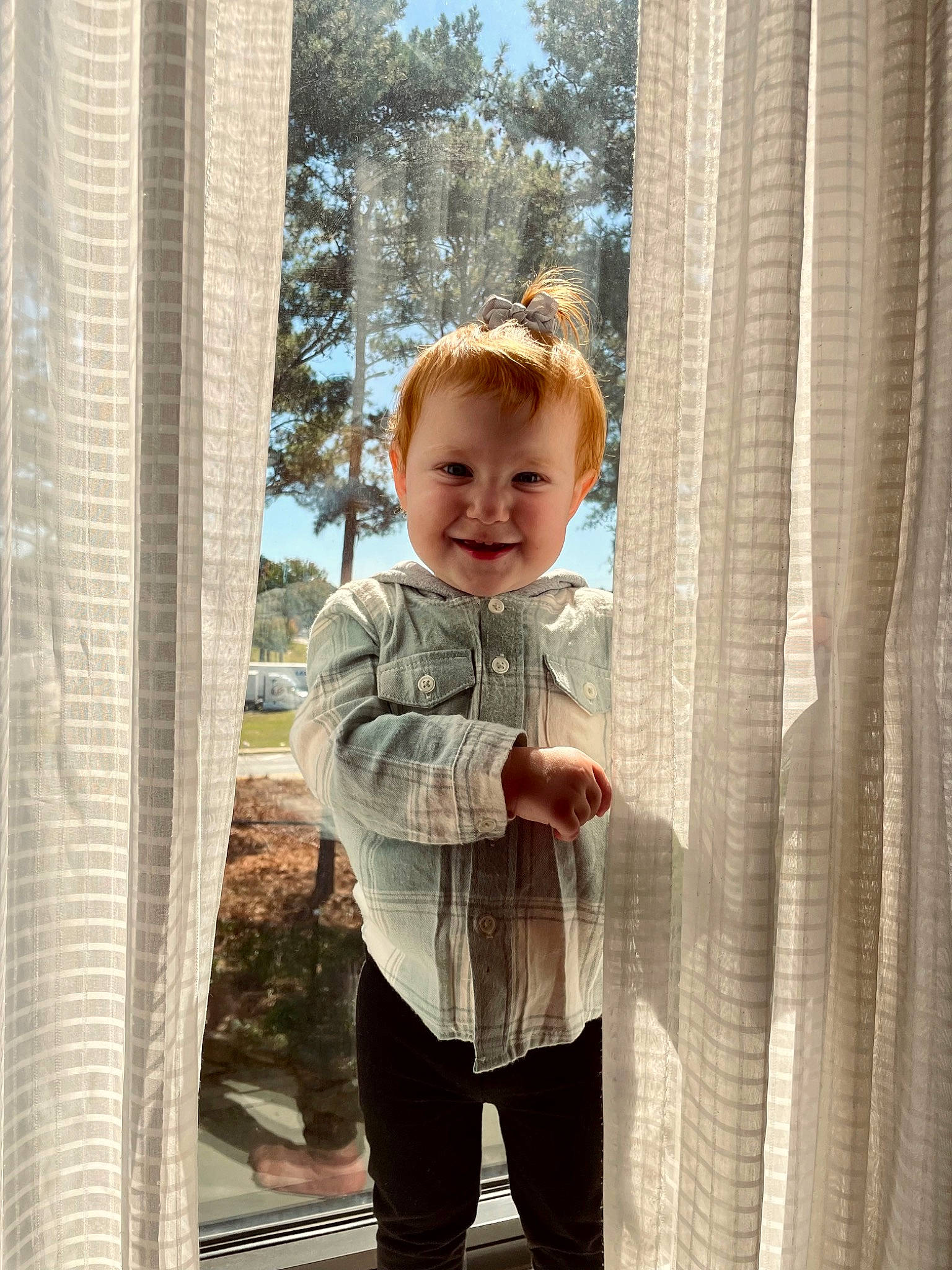 Mackenzie is registered to the contest to win money with this photo: baby, baby_toddler_clothing, child, curtain, flooring, fun, gesture, happy, joy, pattern, people_in_nature, person, room, sitting, sky, sleeve, smile, tints_and_shades, toddler, tree