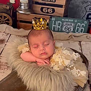 Rose a rejoint le concours — aidez-le/la à gagner de superbes lots ! baby, sleeping, crown, floral_dress, fur_blanket, wooden_prop, vintage_decor, route_66, toy_car, rustic, cozy, peaceful, infant, portrait, indoor, decorative, cute, resting, soft_texture, child