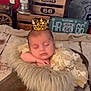 baby, sleeping, crown, floral_dress, fur_blanket, wooden_prop, vintage_decor, route_66, toy_car, rustic, cozy, peaceful, infant, portrait, indoor, decorative, cute, resting, soft_texture, child