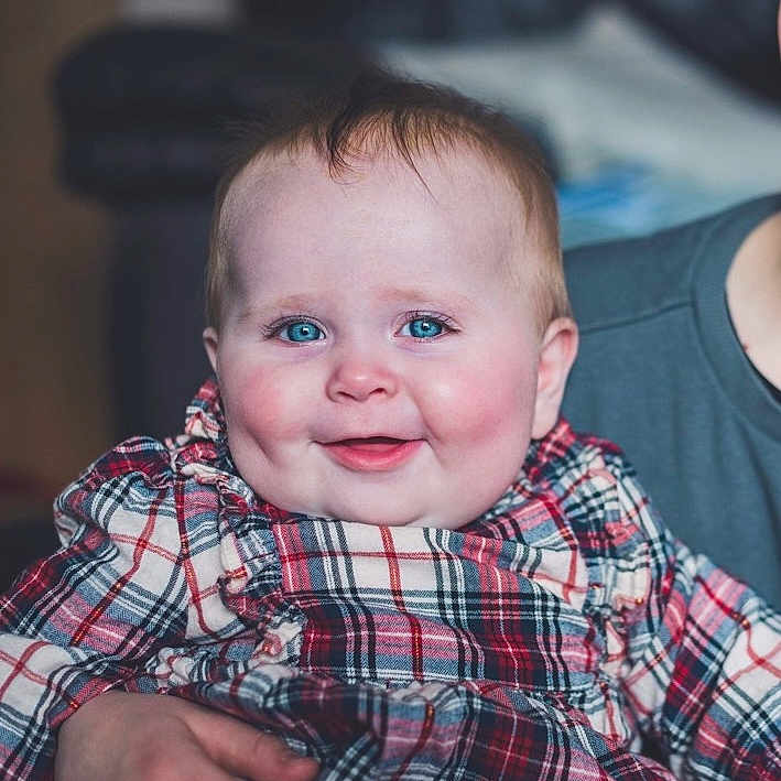 Mia is registered to the contest to win money with this photo: accessories, baby, babylaughing, bodypart, clothing, face, formalwear, happy, head, laughing, mouth, newborn, pants, person, photography, portrait, shirt, sitting, smile, teeth