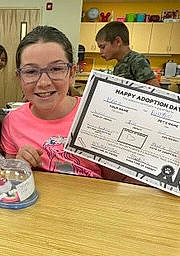 Bryanna is registered to the contest to win money with this photo: child, class, desk, document, education, eyewear, font, hardwood, job, joy, paper, paper_product, person, plate, reading, room, serveware, smile, spoon, t_shirt