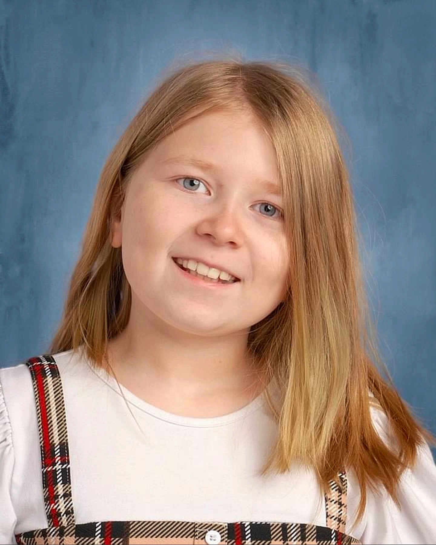 Adaline joined the competition — help win amazing prizes! child, girl, smiling, portrait, blonde_hair, white_shirt, plaid_suspender, blue_background, face, happy, person, casual_clothing, youth, head_and_shoulders, studio_photo, light_skin, long_hair, friendly_expression, school_photo, indoors